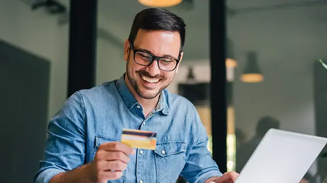 man on laptop holding credit card