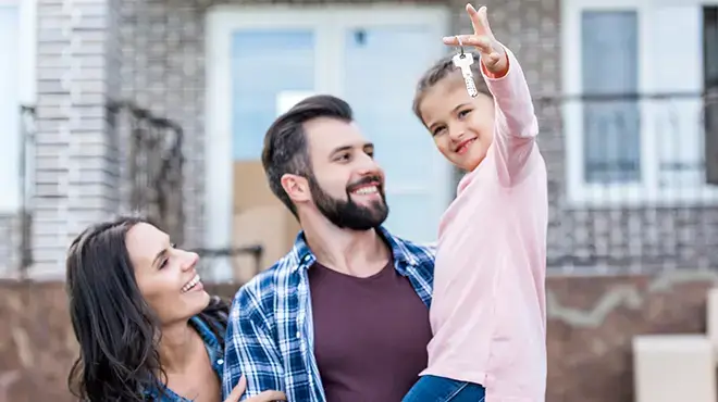 family in front of house holding new keys