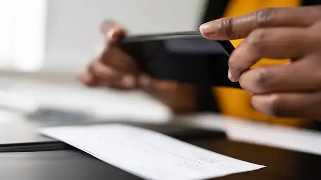 hands holding a mobile phone taking a photo of a check